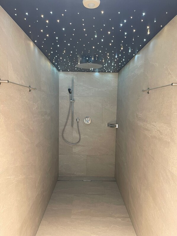 A modern shower with a handheld showerhead and a wall-mounted control panel.