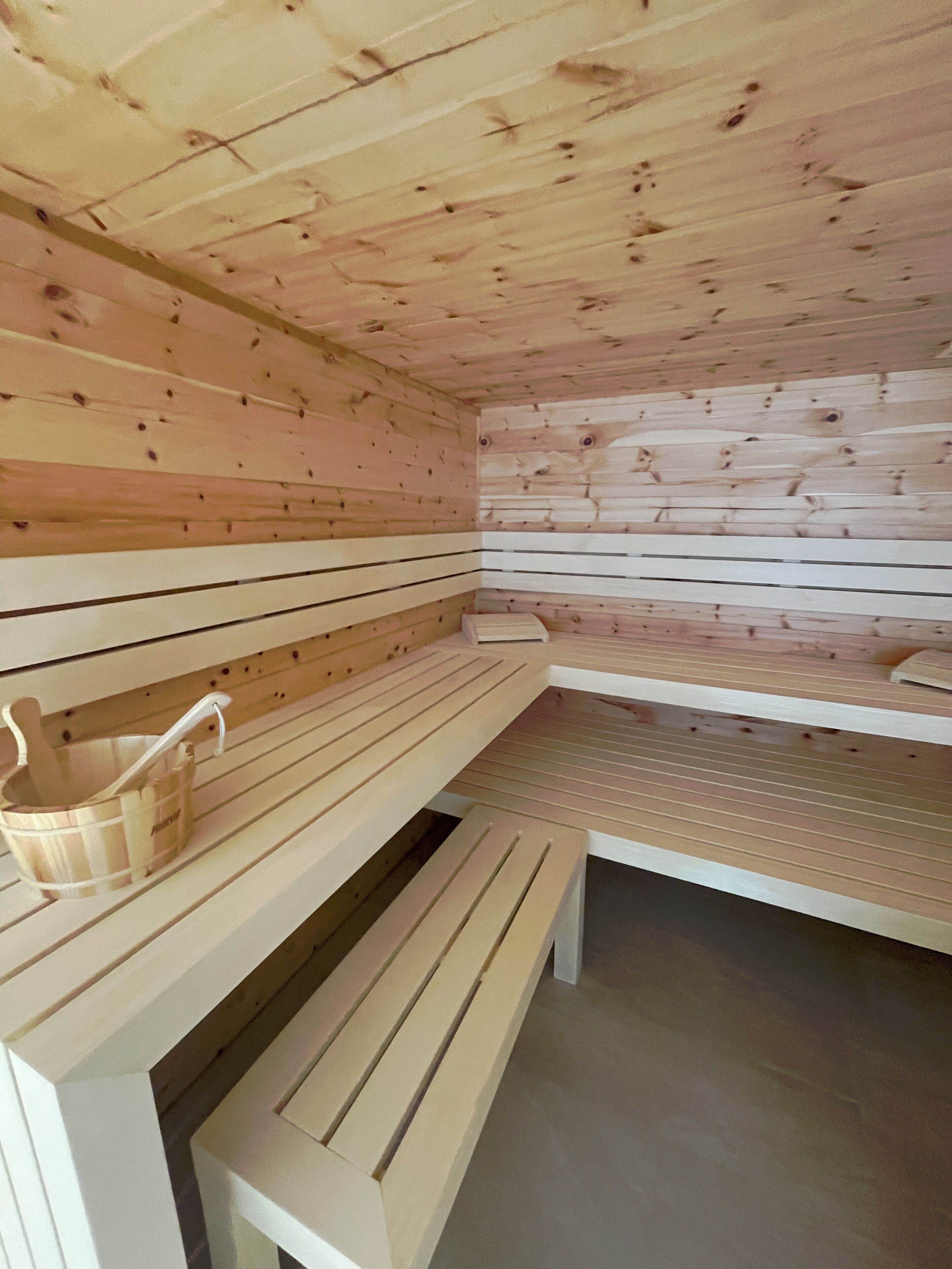 A wooden sauna with benches and a bucket.