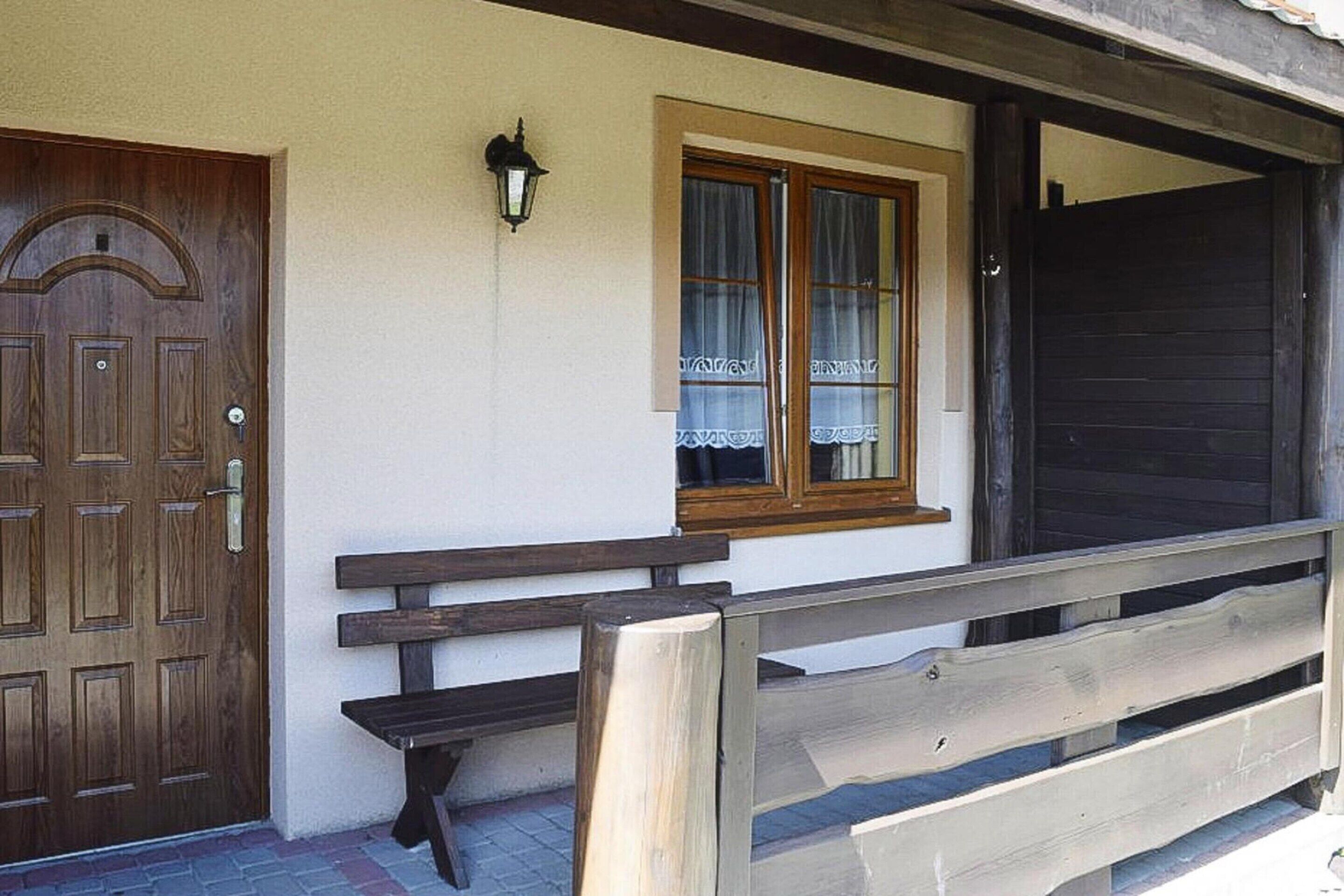 Une porte en bois, un banc et une fenêtre avec des rideaux.