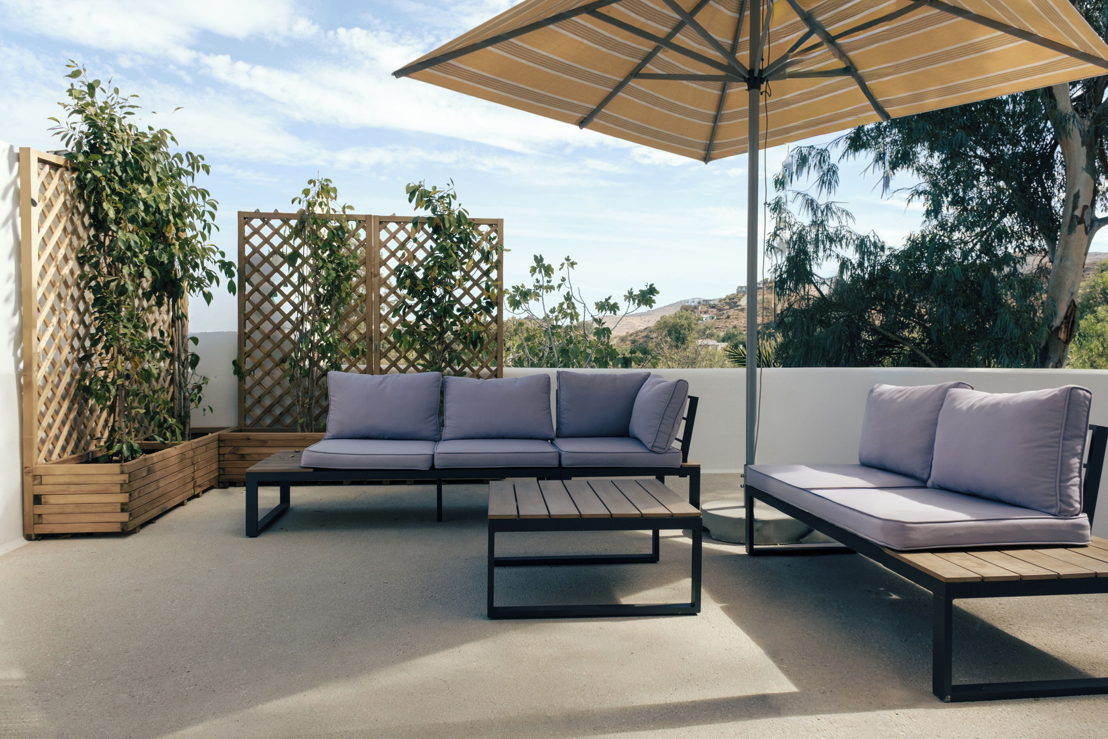 A patio with a sofa, a coffee table, and an umbrella.