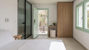 Un dormitorio moderno con cama, una puerta corrediza de vidrio que da a un balcón, un armario de madera y una pequeña mesa con una planta.