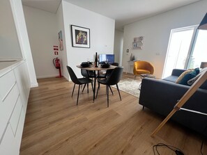 Una sala moderna con comedor, sofá y televisor.
