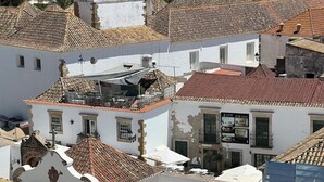 Ein Gebäude mit traditionellem Ziegeldach, weißen Wänden und einem Balkon mit Außenbestuhlung.