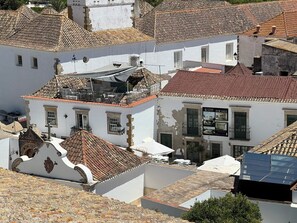 Ein Gebäude mit traditionellem Ziegeldach, weißen Wänden und einem Balkon mit Außenbestuhlung.