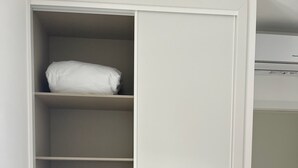 Ein weißer Kleiderschrank mit mehreren Einlegeböden und einer Schiebetür.
