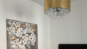 Ein Schlafzimmer mit einem Bett, einem Nachttisch, einer Lampe, einer Deckenleuchte und einem Bild an der Wand.
