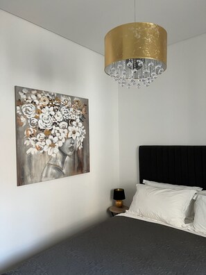 Ein Schlafzimmer mit einem Bett, einem Nachttisch, einer Lampe, einer Deckenleuchte und einem Bild an der Wand.