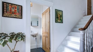 A staircase with white balusters, a wooden door, a potted plant, and a framed picture on the wall. - Charming Three Floor Retreat in Lower Clapton with Friendly Cats and Nature (London)