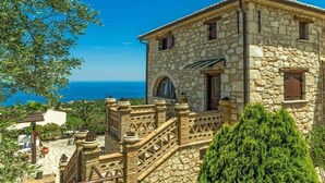 Ein Steinhaus mit Balkon, einer Treppe und Blick auf das Meer.