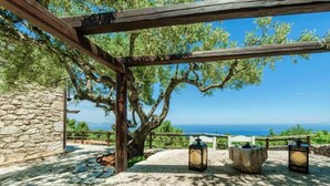 Eine Steinsäule, eine Holzpergola und Meerblick.