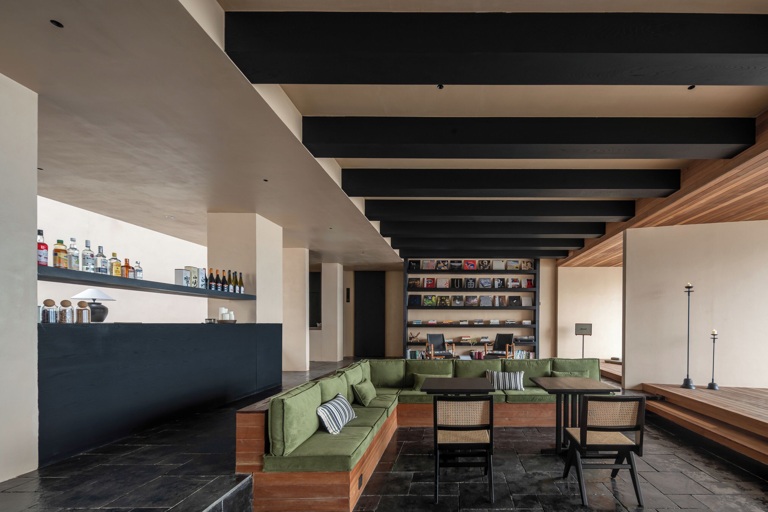 Ein modernes Interieur mit einem grünen Sofa, einem Holztisch und einem Bücherregal voller Bücher.