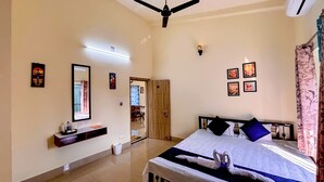 A bedroom with a bed, bedside table, and a ceiling fan. - Swapno Chhobi (Bolpur)