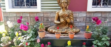 A Buddha statue surrounded by potted plants in a garden setting.