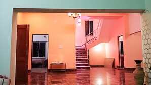 A spacious room with a polished floor, a staircase, and a door leading to another area. - Swapno Chhobi (Bolpur)