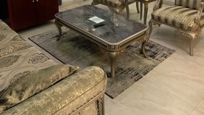 A living room with a television, a red cabinet, a marble coffee table, two armchairs, and a patterned rug. - ELLEX SLEEVES APARTMENT  (Ibadan)