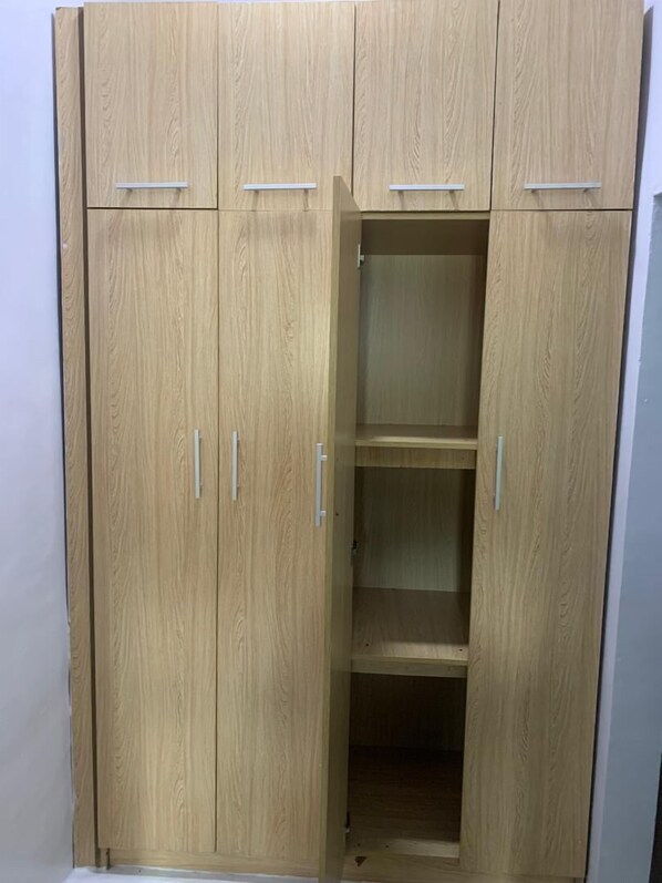 A wooden wardrobe with two doors and a shelf, featuring a simple handle design. - ELLEX SLEEVES APARTMENT (Ibadan)