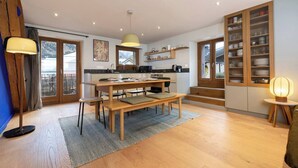 A modern kitchen with wooden cabinets, a dining table, and a built-in oven. - Cozy 4pax | Family | Mt-Blanc View | Central (Chamonix-Mont-Blanc)