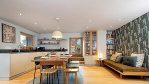 A modern kitchen with a dining area, a sofa, and a bookshelf. - Cozy 4pax | Family | Mt-Blanc View | Central (Chamonix-Mont-Blanc)