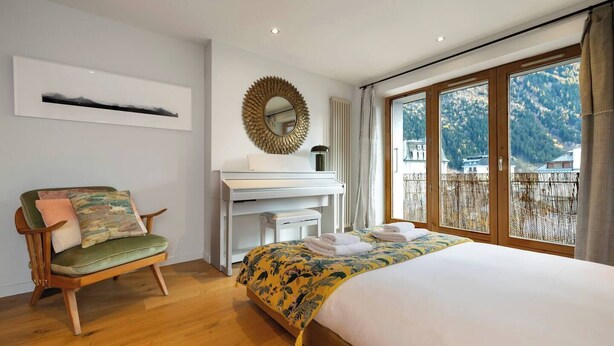 A bedroom with a bed, a desk, a chair, and a large window with a view of mountains. - Cozy 4pax | Family | Mt-Blanc View | Central (Chamonix-Mont-Blanc)