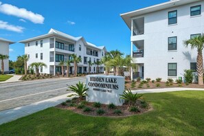 A sign for Hidden Lake Condominiums with a modern white building in the background. - 2BR near Gulf Place w/ Pool, Grill + Free Tickets: Dolphin Cruise & More! (Santa Rosa Beach)