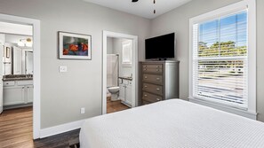 A bedroom with a bed, a dresser, a television, and a bathroom visible through an open door. - 2BR near Gulf Place w/ Pool, Grill + Free Tickets: Dolphin Cruise & More! (Santa Rosa Beach)