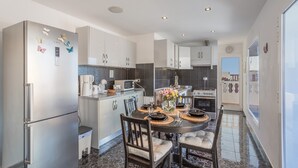 A modern kitchen with a dining area, stainless steel appliances, and a central island.
