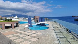 A waterfront promenade with a swimming pool, a bridge, and a view of the sea and distant buildings. - Apartment in the city center with spectacular views and easy access. (Ponta Delgada)