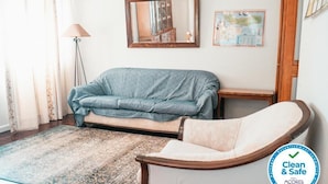 A room with a blue sofa, a white armchair, a patterned rug, a lamp, a mirror, and a map on the wall. - Apartment in the city center with spectacular views and easy access. (Ponta Delgada)