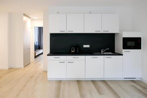 A modern kitchen with white cabinets, a black countertop, and a built-in oven. - Louis and Louise Apartments & Lofts  (Bremen)