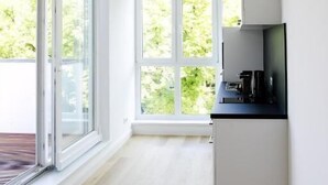 A modern kitchen with large windows, a wooden floor, and a black countertop. - Louis and Louise Apartments & Lofts  (Bremen)