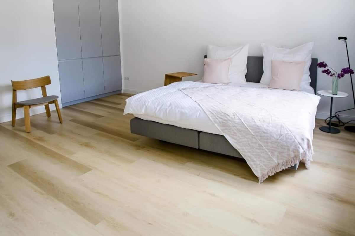 A bedroom with a bed, a chair, a nightstand, and a floor lamp.