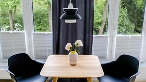 A room with two black chairs, a wooden table, a vase with flowers, and a black pendant light. - Louis and Louise Apartments & Lofts  (Bremen)