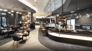 A modern restaurant with a curved bar, seating areas, and a mezzanine level. - The Capital Boardwalk (Gqeberha)