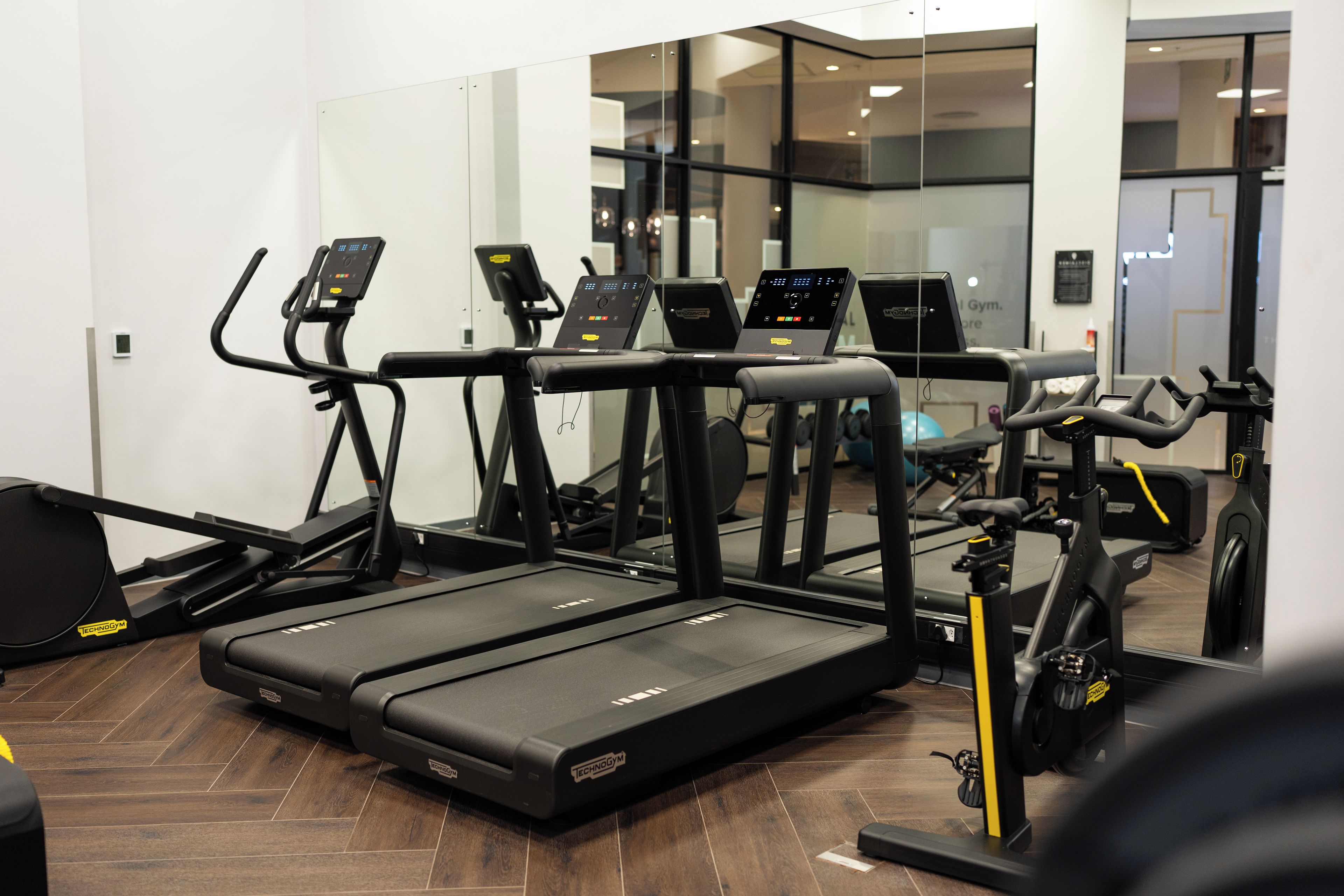 Et fitnessrum med flere løbebånd, crosstrainere og en motionscykel.