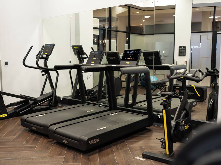 Et fitnessrum med flere løbebånd, crosstrainere og en motionscykel.