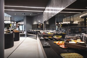 Disposição de buffet com diversos alimentos, uma vitrine de vidro e design de interiores moderno.