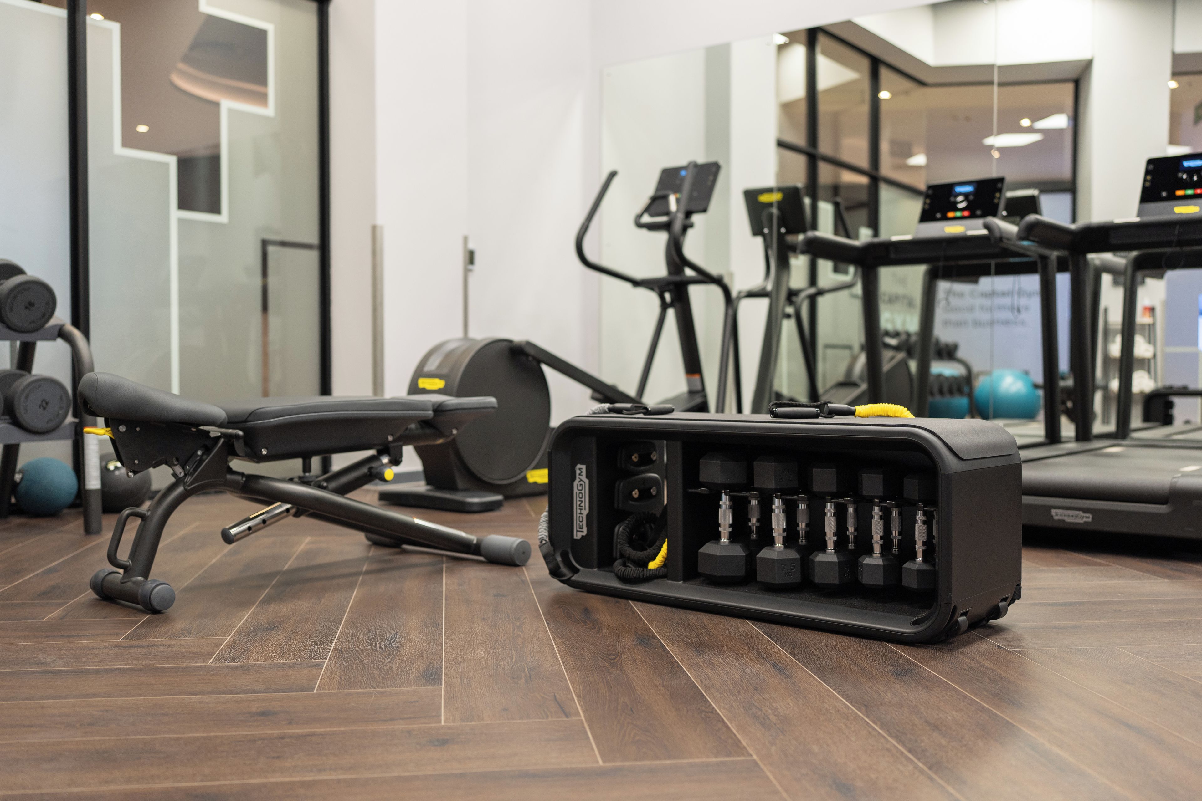 Une salle de sport équipée de matériel d’exercice, notamment un tapis de course, un vélo elliptique et des poids.