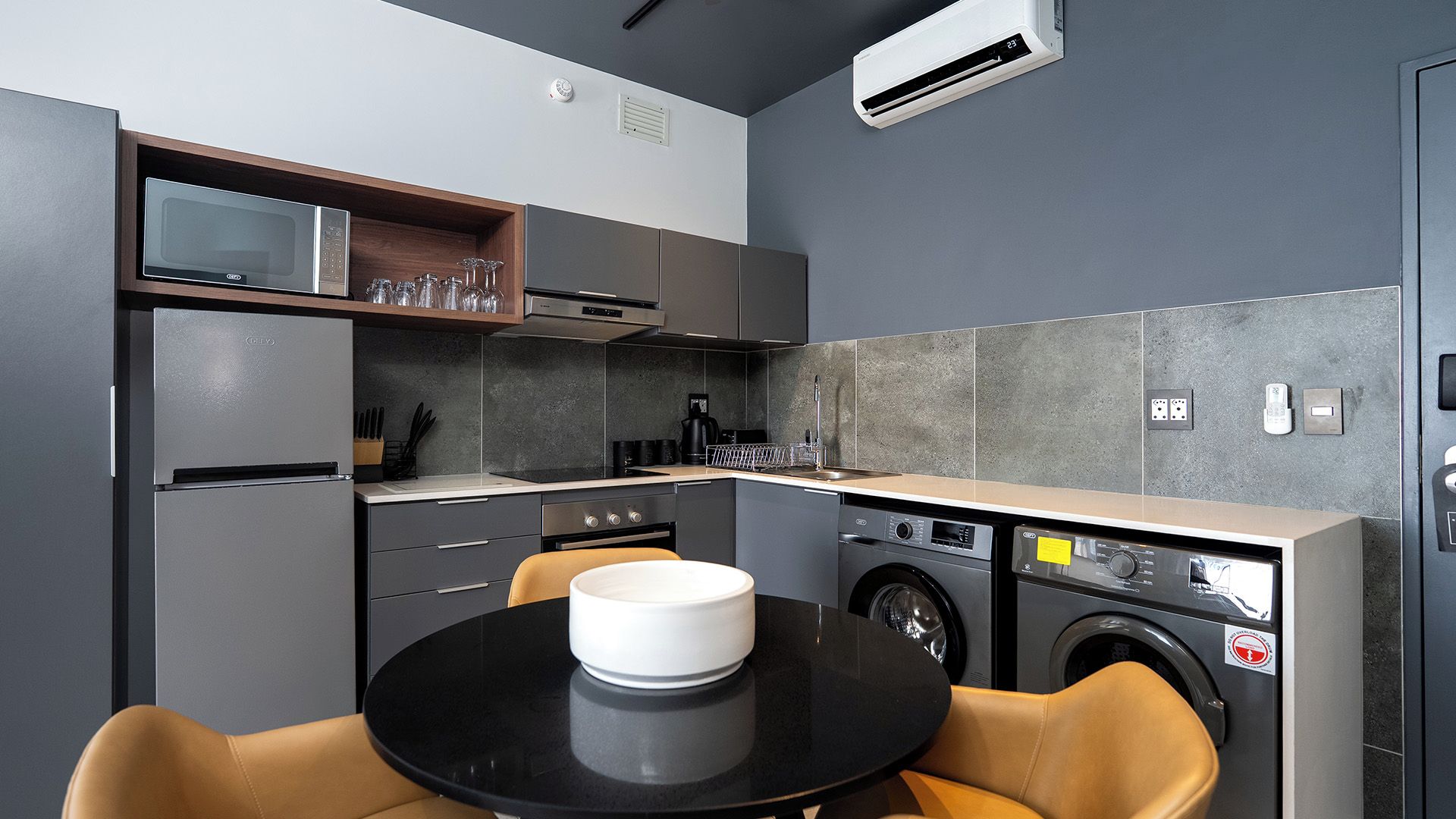 Una cocina compacta con electrodomésticos modernos, una zona de comedor con mesa y sillas, y una lavadora integrada.