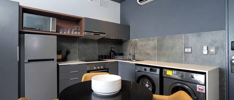 Una cocina compacta con electrodomésticos modernos, una zona de comedor con mesa y sillas, y una lavadora integrada.