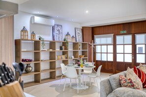 A modern living room with a dining area, wooden shelves, and a white sofa. - Spacious waterfront 1-bedroom apartment GSPI1-1 (Birgu)