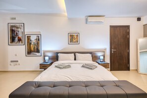 A modern bedroom with a large bed, two bedside tables with lamps, and three framed artworks on the wall. - Spacious waterfront 1-bedroom apartment GSPI1-1 (Birgu)