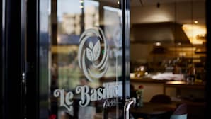 A restaurant with a glass door featuring a logo and the name "Le Basique Addict". - Le Basilic Addis Hotel Apartment & Spa (Addis Ababa)