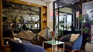 A modern interior with two blue armchairs, a glass coffee table, and a decorative tree sculpture. - Le Basilic Addis Hotel Apartment & Spa (Addis Ababa)