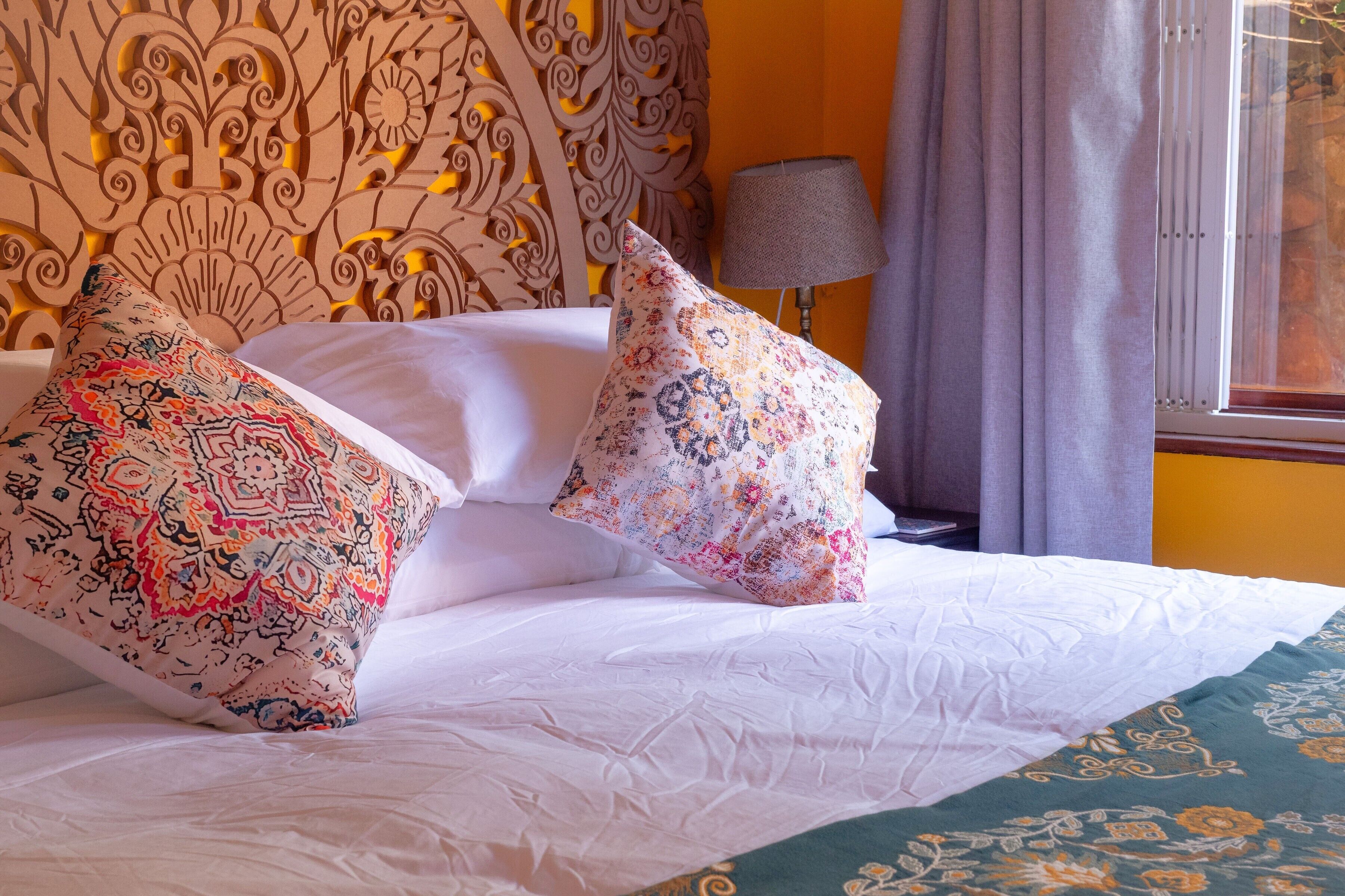 A bed with patterned pillows and a decorative headboard.