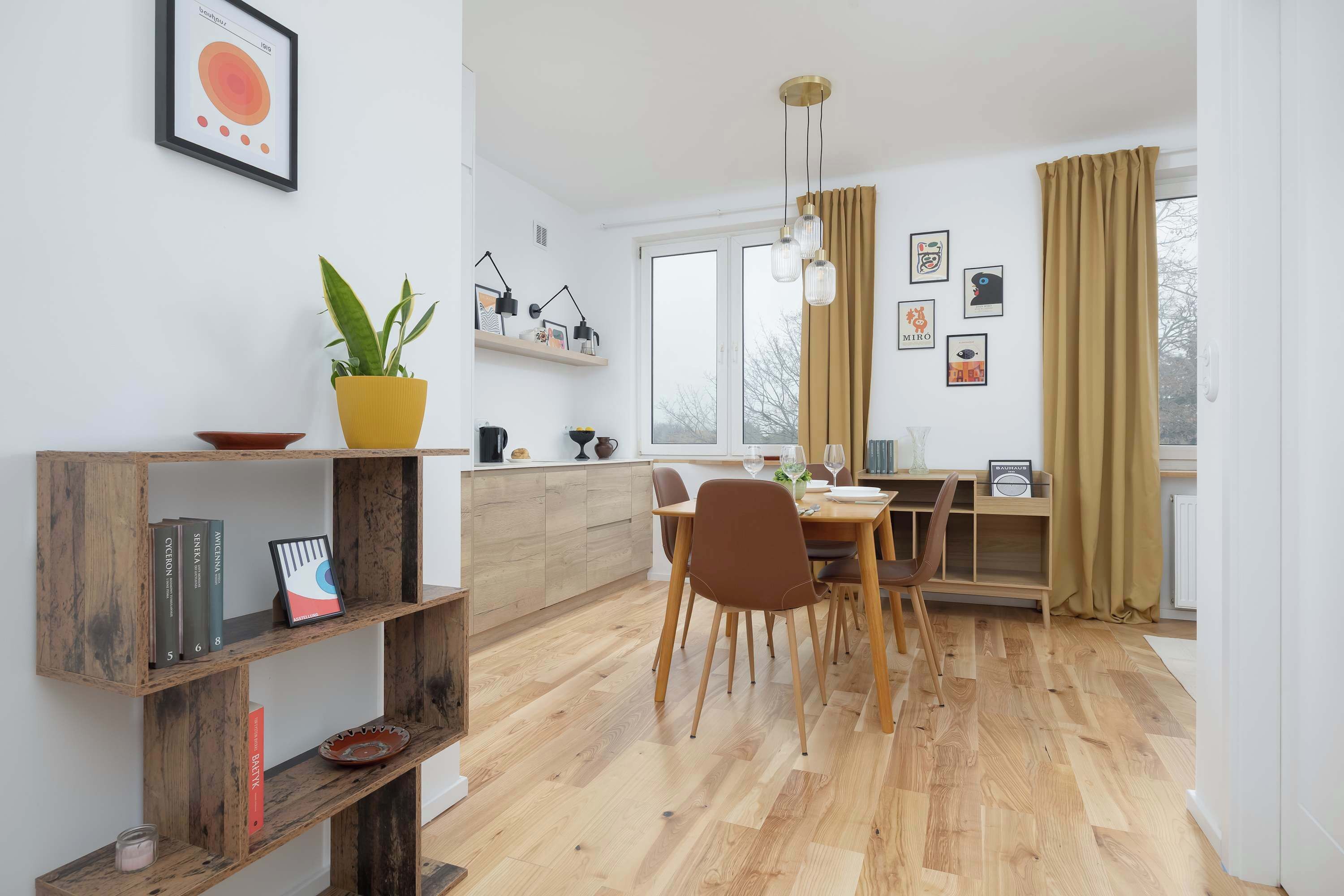 Una cocina moderna con armarios de madera, un comedor con mesa y sillas, y un ventanal con cortinas.