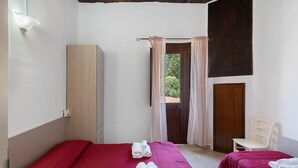 Una habitación con cama, una silla, un armario y una puerta que da a un espacio exterior.
