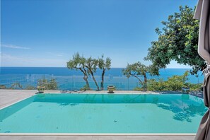 A swimming pool with a view of the sea, surrounded by trees and a clear sky. - Family Room Cilento with Wi-Fi and Air Conditioning (Pisciotta)