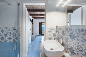 Un bagno con doccia, lavabo e piastrelle decorate.