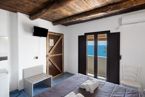 A bedroom with a bed, a chair, a TV, and a view of the sea. - Palinuro Sea View Room with Wi-Fi and Air Conditioning (Pisciotta)