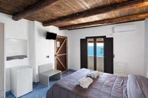 Una camera da letto con un letto, una televisione, una porta in legno e vista sul mare.